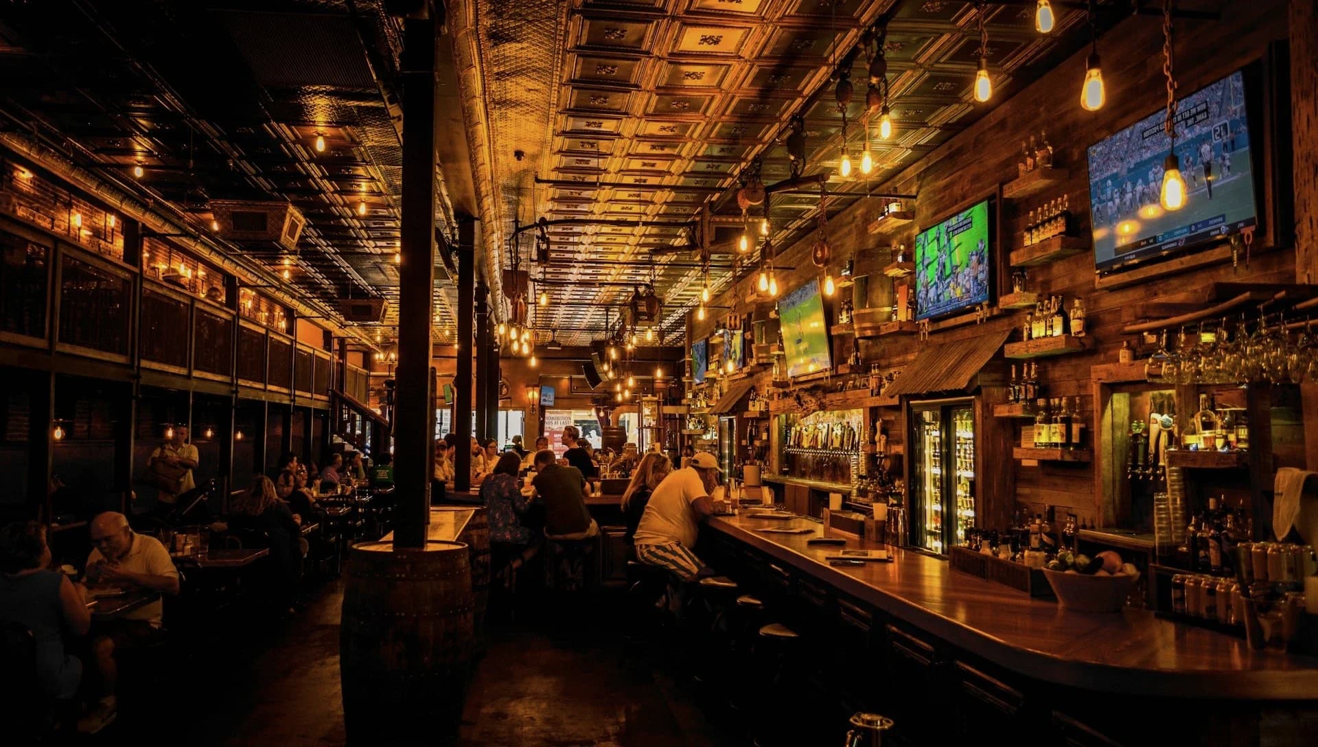 Guests seated along the rail of a warmly lit neighbourhood bar during evening service